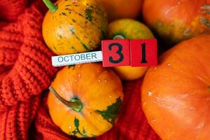 Wooden cube calendar showing October 31st Halloween preparing pumpkins for carving. Holiday and party concept. photo