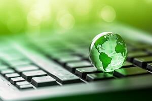 Green globe on a laptop keyboard with green bokeh background. photo