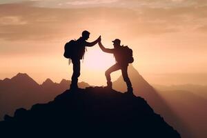 Silhouette of two men with backpacks on the top of the mountain. photo