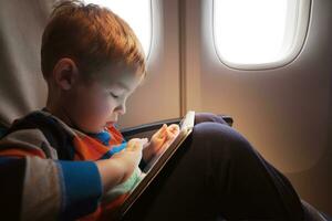 Child using tablet computer during flight photo