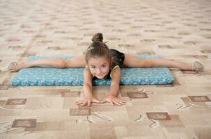 pequeño niña haciendo pierna dividida en el piso foto