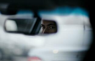 Man looking in the rear view mirror while driving photo