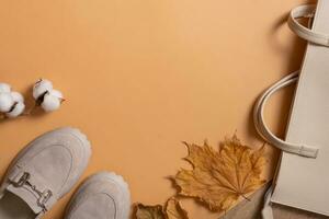 Woman's shoes, bag with autumn leaves on orange background with copy space top view, flat lay photo