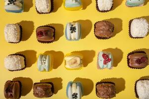 Set of different macaroons on yellow background top view, flat lay. Sweet wood pattern background. photo