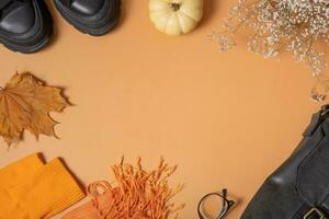 Woman's shoes with autumn leaves and pumpkin on orange background. Casual fashion with copy space top view, flat lay photo