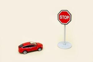toy red car in front of a stop sign on a light background with copy space photo