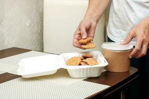 madre recoge almuerzo para el niño, galletas en el caja de almuerzo, sopa en el sopa envase. foto