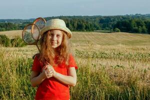 niña en un Paja sombrero con bádminton raquetas en su manos foto
