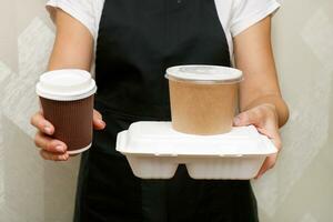 a woman holds out a ready order with food in takeaway containers photo