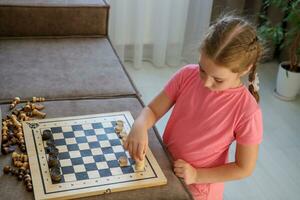 girl plays an invented game at home with a chessboard, checkers and chess photo