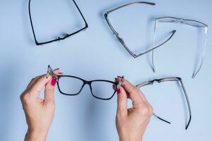 Eyeglasses in female hand on blue background.  Optical store, vision test, stylish glasses concept photo