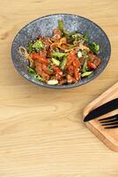 un cuenco de udon fideos, ternera y frito vegetales ángulo ver en de madera mesa foto