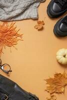 Woman's black shoes with autumn leaves and pumpkin on orange background with copy space top view, flat lay photo