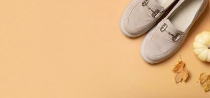 Banner with suede shoes with autumn leaves and pumpkin on orange background top view, flat lay photo