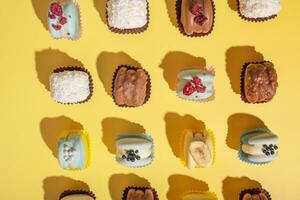 Set of different beautiful macaroons on yellow background top view, flat lay photo