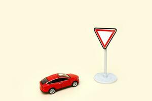 toy red car in front of a traffic sign give way on a light background with copy space photo