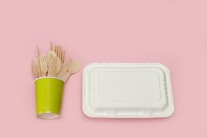 disposable wooden spoons, forks and knives in a paper cup with a corn raw lunchbox container photo