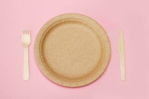 paper disposable plate with bamboo fork and knife on pink background photo