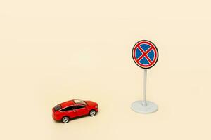 juguete rojo coche en frente de un la carretera firmar No parada en un beige antecedentes con Copiar espacio foto