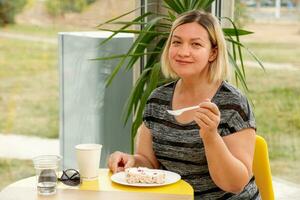 mujer en café felizmente comiendo postre foto