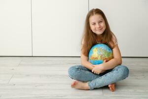 happy girl hugging the globe while sitting on the floor cross-legged photo