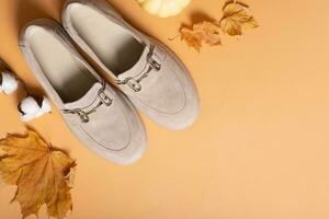 Suede shoes with autumn leaves and cotton candy on orange background top view, flat lay. Copy space photo