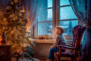 un pequeño chico sentado en un silla mira en admiración a el decorado Navidad árbol foto