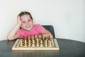 sonriente niña en frente de ajedrez conjunto fuera para jugar foto