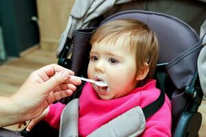 mother feeds baby sitting in stroller photo