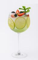 Drink with berries, with lime slices and mint in a wine glass photo