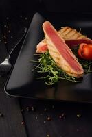 Grilled tuna steak on black plate - soft focus point photo