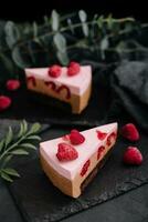 Pieces of cheesecake with raspberries on black board photo