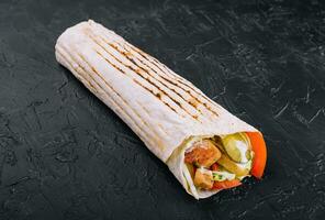 Delicious shawarma on a wooden board on a dark wooden table photo