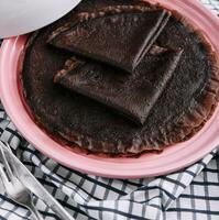 Chocolate pancake on pink plate close up photo