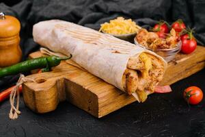 Delicious shawarma on a wooden board on a dark wooden table photo