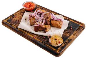 Serving of barbecue with sauce and pickled onions on a wooden board photo