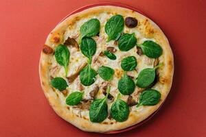 Hot mushroom pizza with basil on red plate photo