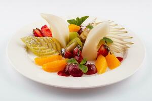 Fresh fruit salad on white plate isolated on white photo