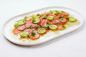 Buffet serving of pickled salmon slices with radish, cucumber photo