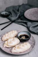 uncooked asian dumplings with soy sauce photo