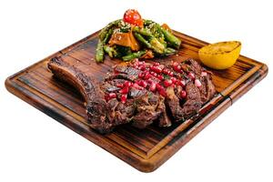 Sliced grilled pork steak with pomegranate seeds and asparagus photo