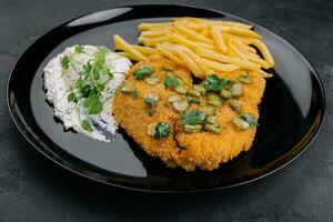 Delicious wiener hunter schnitzel with sauce and french fries close-up on a plate photo