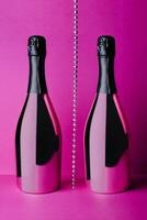 two champagne bottles on pink background photo