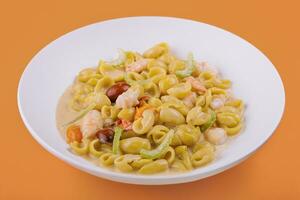 Italian dish macarana with shrimp on yellow background photo