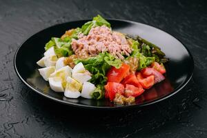 Tuna and vegetable salad on black plate photo