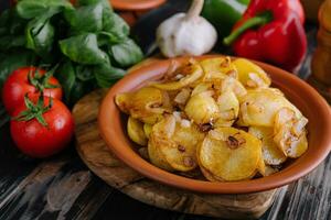 Fried potatoes with onions on wooden tray photo