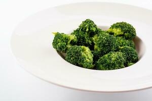 Fresh green broccoli in white circle plate isolated on white photo