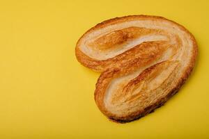 Butterfly puff pastry or palmier cookie on yellow background photo