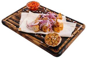 Chicken fillet skewers on tortilla served with red onion photo