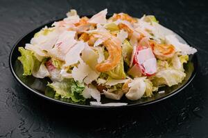 Delicious fresh caesar salad on black plate photo